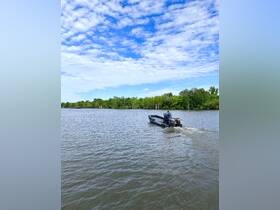 A speedboat navigates through calm waters under a bright blue sky, showcasing the beauty of a day on the water.
