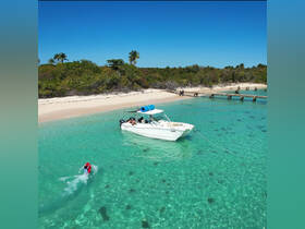 A vibrant scene of a child swimming in clear turquoise waters near a boat, with a picturesque beach in the background — perfect for family adventures and fun in the sun.