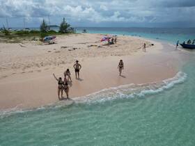 A lively group enjoys a day at the beach, capturing fun moments at a sandbar stop with clear turquoise waters and soft sandy shores.