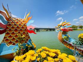 A vibrant view of a decorative boat adorned with colorful designs and flowers, set against a serene waterfront backdrop, perfect for sightseeing and cultural experiences.