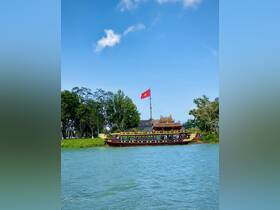 A beautifully crafted boat docked along a serene river in Vietnam, showcasing traditional design against a clear blue sky.