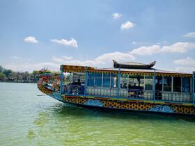 A vibrant dragon boat glides through calm waters, showcasing its intricate design and structure — perfect for scenic tours and cultural experiences.