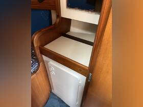 Interior view of a cozy boat cabin featuring wooden furnishings and a storage compartment, ideal for relaxing and enjoying time on the water.