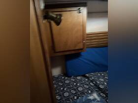 Interior view of a cozy cabin space on a boat, featuring wooden cabinetry and patterned bedding, perfect for relaxing during a voyage.