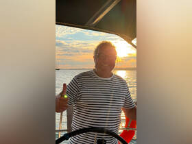 A cheerful individual gives a thumbs-up while enjoying a beautiful sunset on the water, capturing the essence of a perfect boating experience.