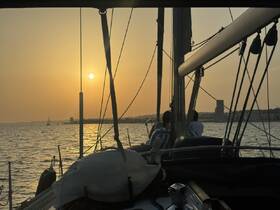 A serene sunset view from a sailboat, with guests enjoying the tranquil waters — perfect for a relaxing sailing experience.