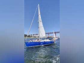A lively group enjoys a sailing trip on a blue yacht, with a stunning bridge in the background — perfect for memorable outings on the water.
