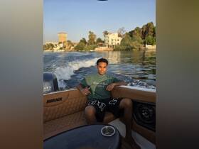 A young man relaxes on a boat, enjoying the scenic views along the waterway — a perfect moment for leisure and exploration.