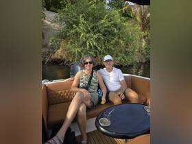 A couple enjoys a relaxing moment on a boat, surrounded by lush greenery — perfect for a serene getaway on the water.