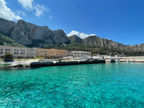 A stunning view of a serene harbor surrounded by majestic mountains and crystal-clear waters, perfect for exploring the natural beauty of the coastline.