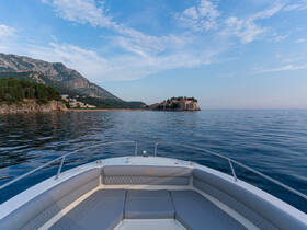 A serene view from the front of a boat, showcasing the calm waters and picturesque coastline, perfect for exploring scenic destinations.