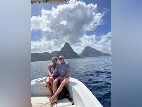 A couple enjoys a romantic moment on a boat with stunning mountain scenery in the background, perfect for memorable adventures on the water.
