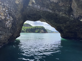 A stunning view through a natural rock arch, showcasing the beautiful coastline and tranquil waters — a perfect highlight of a boating adventure.