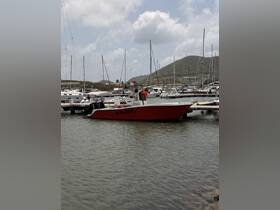 A vibrant red boat named 'Integrity' docked at a marina, surrounded by various other vessels and scenic hills in the background.