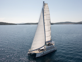 A stunning aerial view of a catamaran sailing through calm waters, showcasing the vessel's sleek design and the serene coastal landscape.