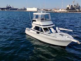 A sleek yacht navigates through the water, showcasing its elegant design against a backdrop of naval vessels — perfect for luxury outings or fishing trips.