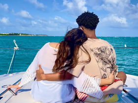A couple enjoys a romantic moment on the bow of a boat, surrounded by stunning ocean views — perfect for intimate getaways or sunset cruises.