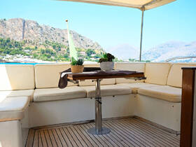 A cozy lounge area inside a yacht featuring comfortable seating and a stylish table, perfect for relaxing while enjoying scenic views.