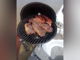 A delicious spread of grilled steaks and sausages on a barbecue aboard a boat, perfect for a day of fun on the water.