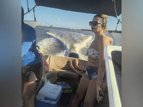 A woman enjoys a day on the water while seated on a boat, with a view of the wake behind them — perfect for adventure seekers and boating enthusiasts.