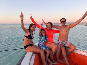 A joyful family poses on the boat, celebrating together with the sunset in the background — a perfect moment for fun and bonding on the water.