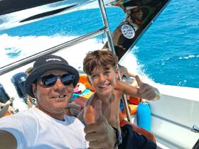 A joyful moment captured on a boat with a man and a boy giving thumbs up, showcasing the fun and excitement of their boating adventure.