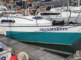 A close-up view of the 'SKULMARTIN' yacht docked at the marina, showcasing its sleek design and vibrant colors.