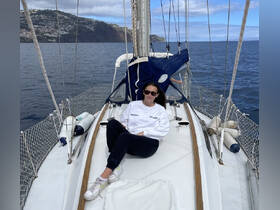 A woman relaxes on the deck of a sailboat, enjoying the serene ocean views — a perfect moment for sailing enthusiasts.