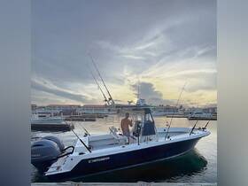 A man poses on a fishing boat named 'Contender' at a marina during sunset, showcasing the perfect setting for a fishing adventure.