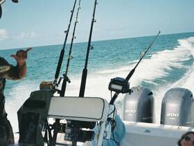 A fisherman enjoys a day on the water, showcasing fishing rods and the thrill of the catch while cruising through beautiful turquoise waters.