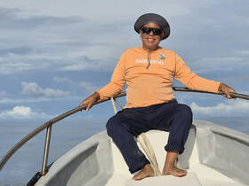 A smiling man enjoys a moment aboard a boat, showcasing the joy of ocean adventures and fishing experiences.