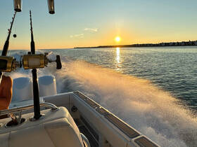A stunning sunset view from a fishing boat, showcasing the serene waters and the excitement of a fishing trip. Perfect for capturing the essence of a day on the water.