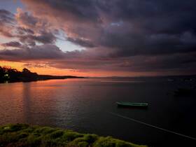 A stunning sunset casts vibrant colors over the tranquil waters, creating a picturesque coastal scene perfect for evening reflections.