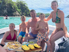 A joyful family enjoys snacks aboard a boat, surrounded by stunning turquoise waters — perfect for memorable family outings and celebrations.