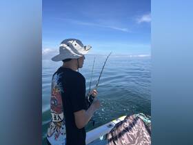 A young boy enjoys a fishing experience on a calm ocean, showcasing the thrill of angling in a beautiful setting.