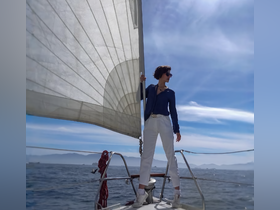 A woman confidently sails on a boat, enjoying the ocean breeze and adventure on the water — a perfect moment for sailing enthusiasts.