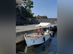A charming boat named 'Giniusa' docked at a scenic waterfront, showcasing its inviting design and tranquil surroundings.