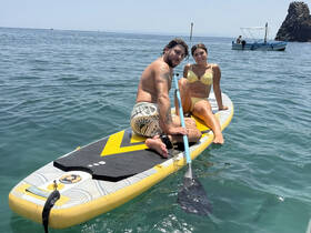 A couple enjoys paddleboarding together in clear waters, capturing the essence of summer fun and adventure on the water.