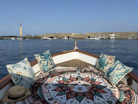 A cozy interior view of a boat featuring decorative cushions and a vibrant tapestry, perfect for relaxing on the water.