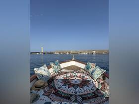 A cozy interior view of a boat featuring decorative cushions and a vibrant tapestry, perfect for relaxing on the water.