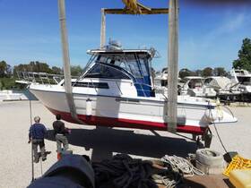 A boat is being lifted at a dock, showcasing its exterior while two individuals observe the process. Ideal for showcasing boat maintenance and handling.