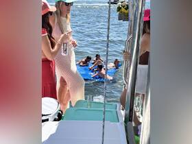 A lively group enjoys a fun day on the water, with friends relaxing on a floating mat while others socialize on the boat — perfect for summer parties and aquatic adventures.