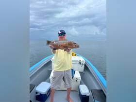 A proud angler holds up his catch aboard a fishing boat, showcasing the thrill of a successful day on the water.