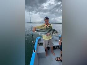 An angler proudly displays his catch aboard a fishing boat, showcasing the thrill of deep-sea fishing adventures.