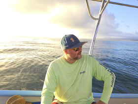 A man enjoys a serene moment on a boat, gazing at the tranquil waters, perfect for capturing the essence of a relaxing day on the sea.