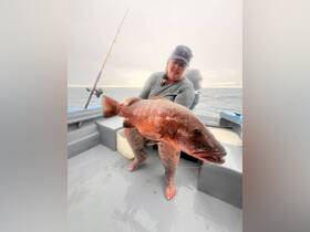 A woman proudly displays her impressive catch while fishing on a boat, showcasing the thrill of deep-sea fishing adventures.