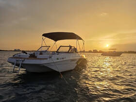 A serene sunset view of a boat anchored in calm waters, showcasing the vessel's sleek design against a golden sky.