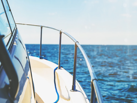 A close-up view of the side of a boat gliding through the ocean, showcasing the sleek hull and clear blue waters — perfect for boating enthusiasts.