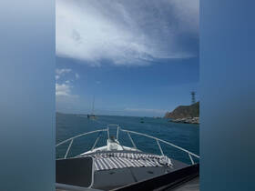 A scenic view from the front of a yacht cruising through calm waters, showcasing the beautiful sky and distant coastline.