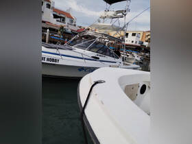 A close-up view of a fishing boat named 'THE HOBBY' docked at a marina, showcasing its structure and design.